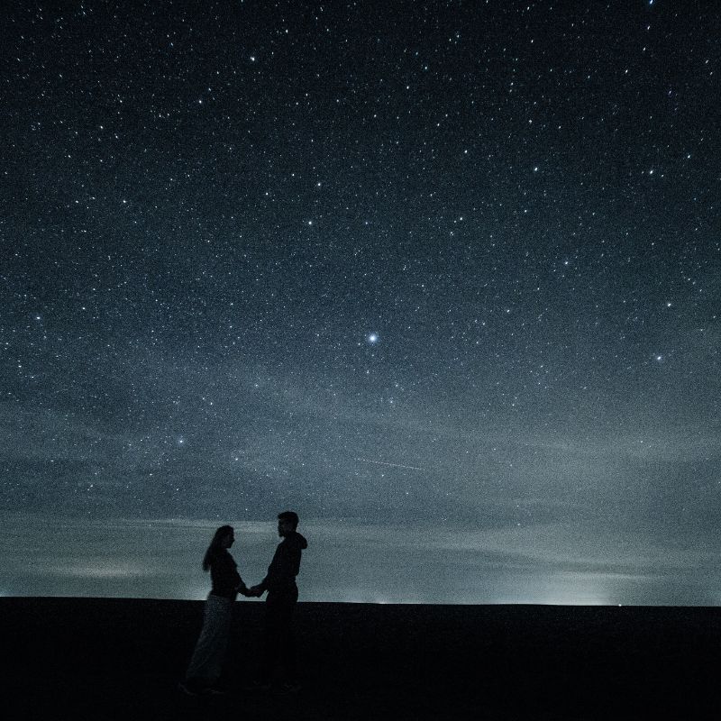 Couple observant un ciel étoilé lors d’une escapade romantique en hiver